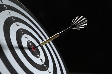 Photo of Targeting. Dart board with arrow on black background, closeup