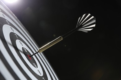 Photo of Targeting. Dart board with arrow on dark background, closeup