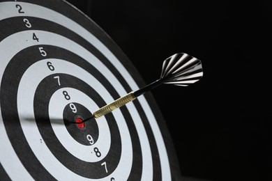 Photo of Targeting. Dart board with arrow on black background, closeup