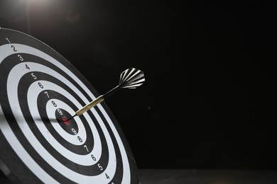 Photo of Targeting. Dart board with arrow on dark background, space for text
