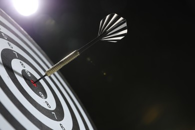 Photo of Targeting. Dart board with arrow on dark background, closeup