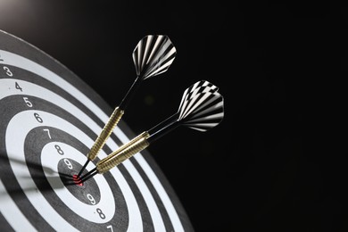 Photo of Targeting. Dart board with arrows on black background, closeup. Space for text