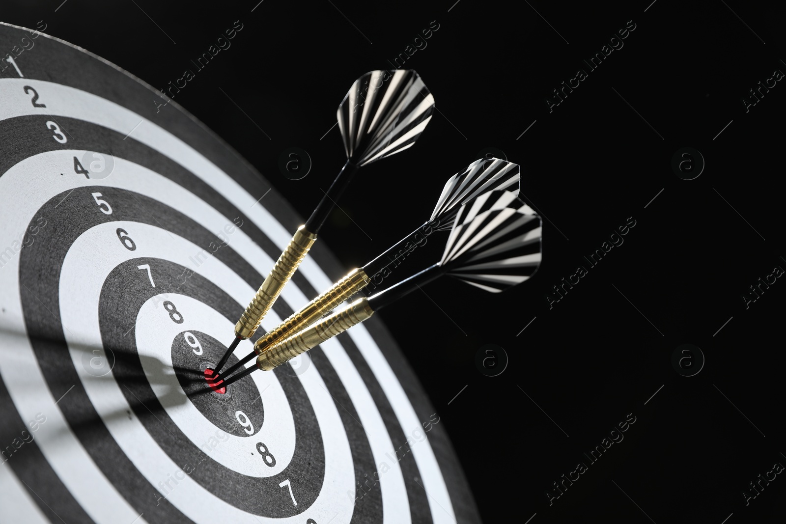 Targeting. Dart board with arrows on black background, closeup Photo of Targeting. Dart board with arrows on black background, closeup