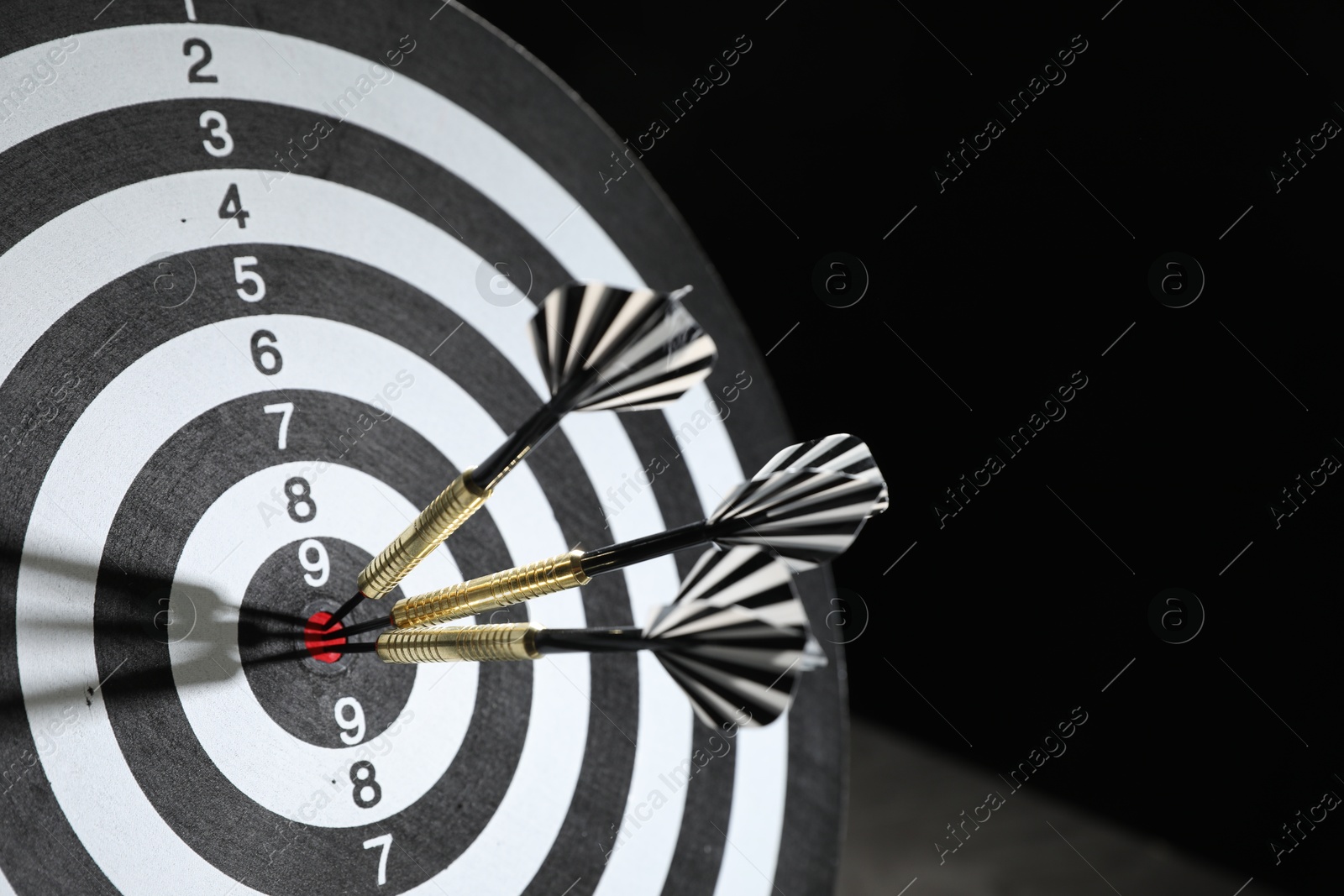 Targeting. Dart board with arrows on black background, closeup. Space for text Photo of Targeting. Dart board with arrows on black background, closeup. Space for text