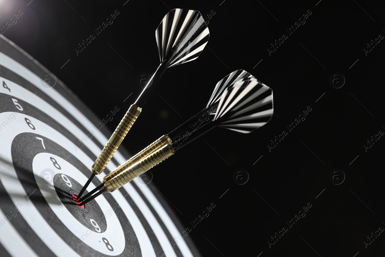 Targeting. Dart board with arrows on dark background, closeup Photo of Targeting. Dart board with arrows on dark background, closeup