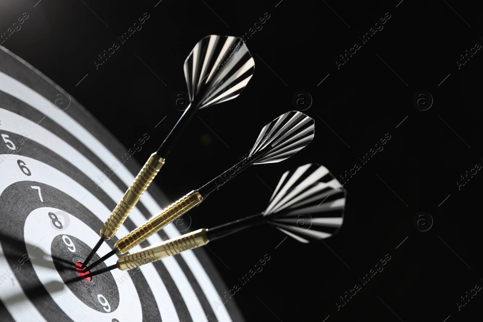 Targeting. Dart board with arrows on dark background, closeup Photo of Targeting. Dart board with arrows on dark background, closeup
