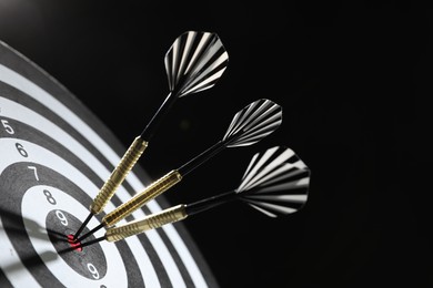 Photo of Targeting. Dart board with arrows on dark background, closeup