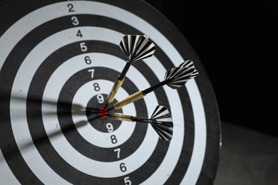 Photo of Targeting. Dart board with arrow on black background, closeup