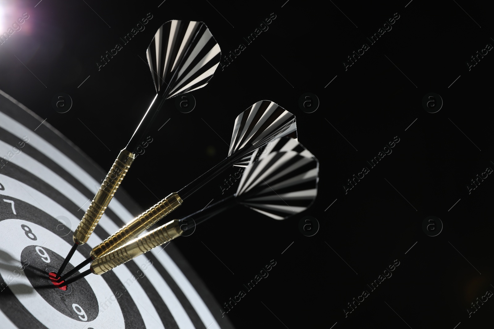 Targeting. Dart board with arrows on dark background, closeup Photo of Targeting. Dart board with arrows on dark background, closeup