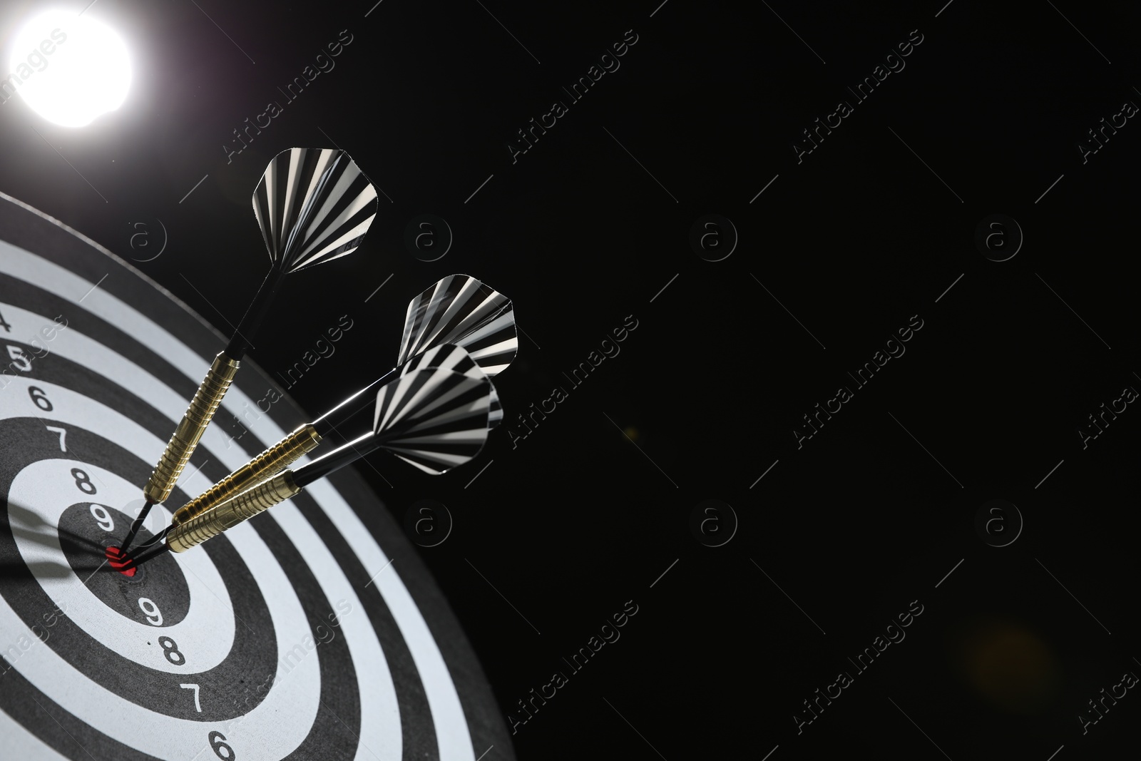 Targeting. Dart board with arrows on dark background, closeup. Space for text Photo of Targeting. Dart board with arrows on dark background, closeup. Space for text