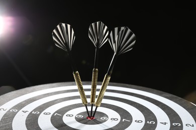 Photo of Targeting. Dart board with arrows on dark background, closeup
