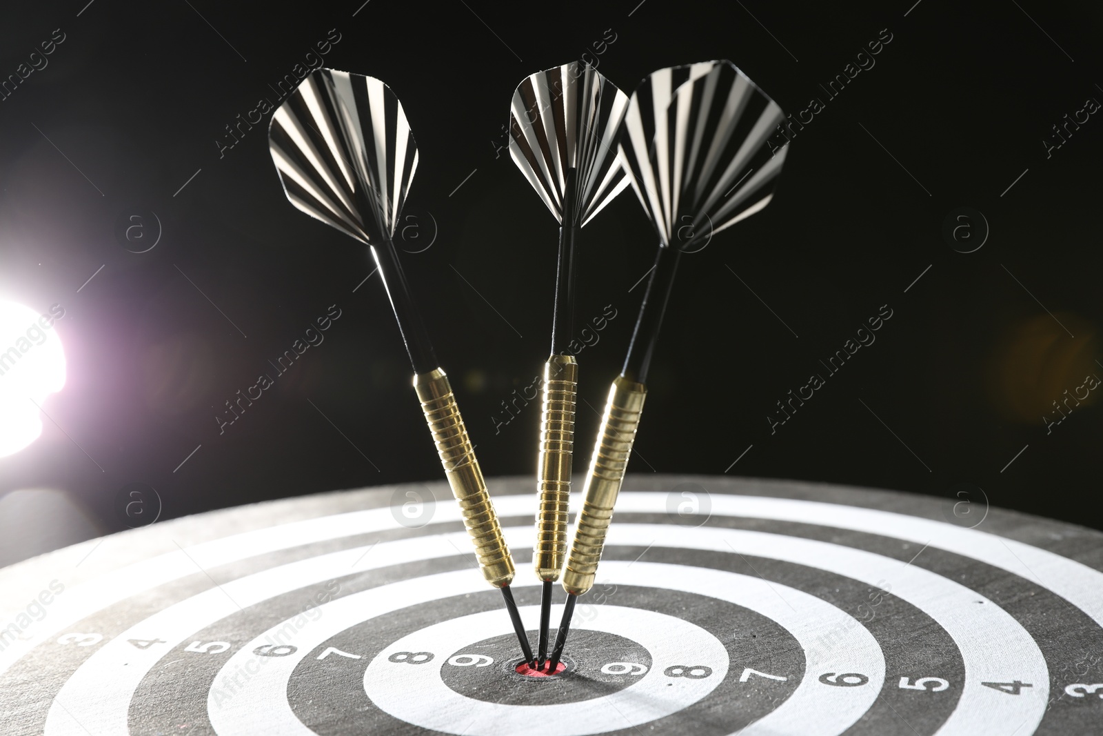 Targeting. Dart board with arrows on dark background, closeup Photo of Targeting. Dart board with arrows on dark background, closeup