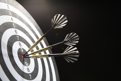 Photo of Targeting. Dart board with arrows on dark background, closeup