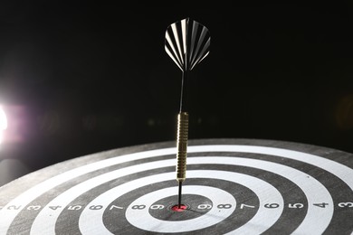Photo of Targeting. Dart board with arrow on dark background, closeup