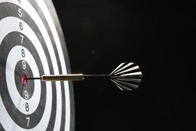 Photo of Targeting. Dart board with arrow on dark background, closeup