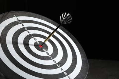 Photo of Targeting. Dart board with arrow on dark background, closeup