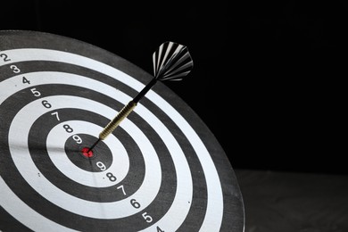 Photo of Targeting. Dart board with arrow on dark background, closeup