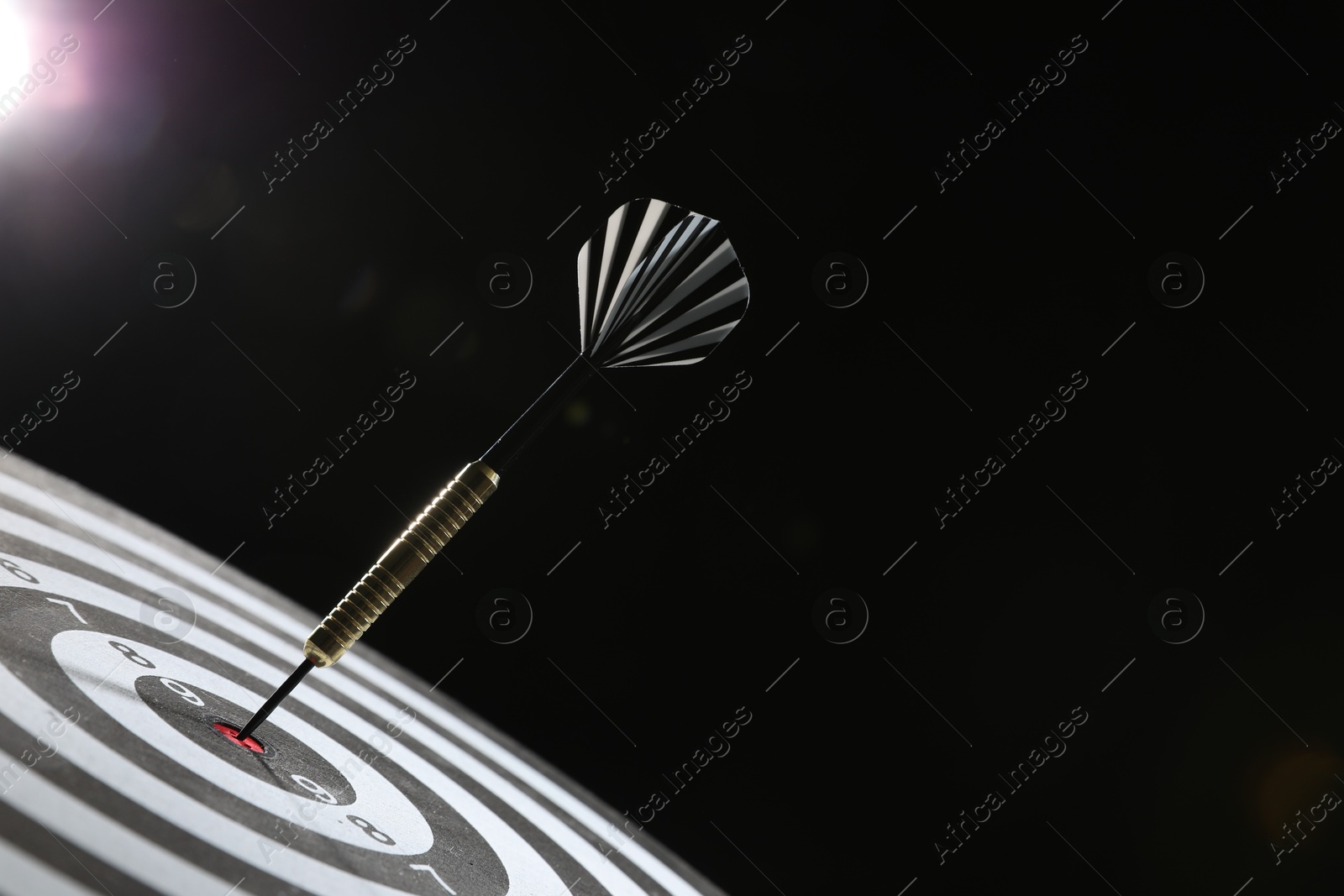Targeting. Dart board with arrow on dark background, closeup. Space for text Photo of Targeting. Dart board with arrow on dark background, closeup. Space for text