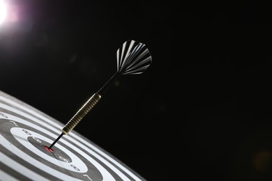 Photo of Targeting. Dart board with arrow on dark background, closeup. Space for text