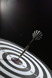 Photo of Targeting. Dart board with arrow on dark background, closeup