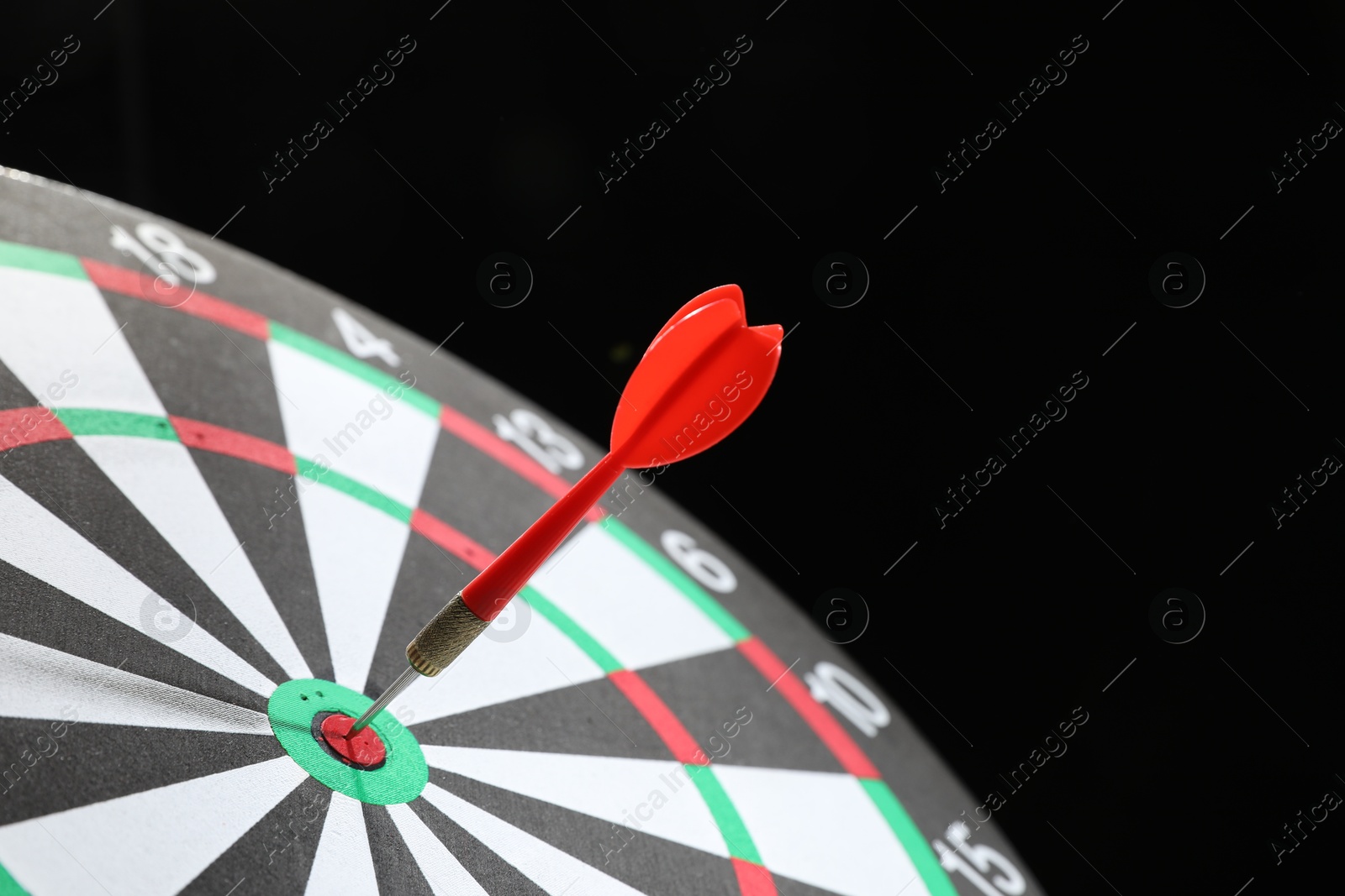 Targeting. Dart board with arrow on black background, closeup Photo of Targeting. Dart board with arrow on black background, closeup