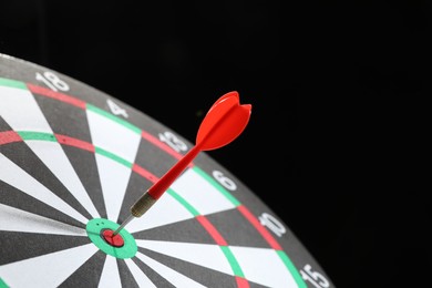 Photo of Targeting. Dart board with arrow on black background, closeup