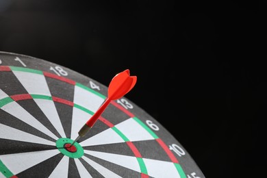 Photo of Targeting. Dart board with arrow on dark background, closeup