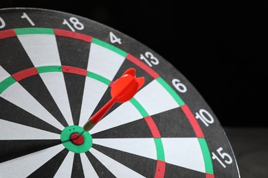 Photo of Targeting. Dart board with arrow on dark background, closeup