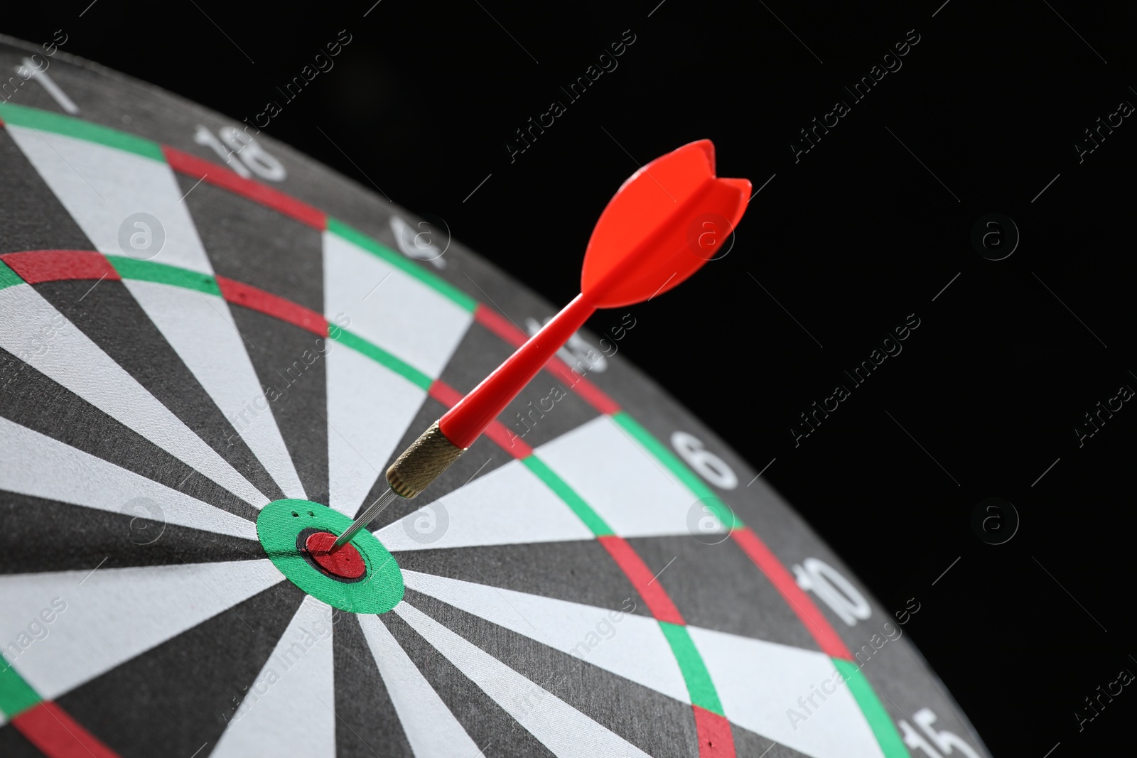 Targeting. Dart board with arrow on black background, closeup Photo of Targeting. Dart board with arrow on black background, closeup