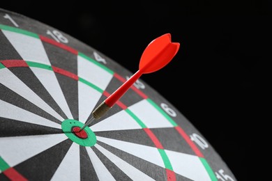 Photo of Targeting. Dart board with arrow on black background, closeup