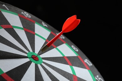 Photo of Targeting. Dart board with arrow on black background, closeup