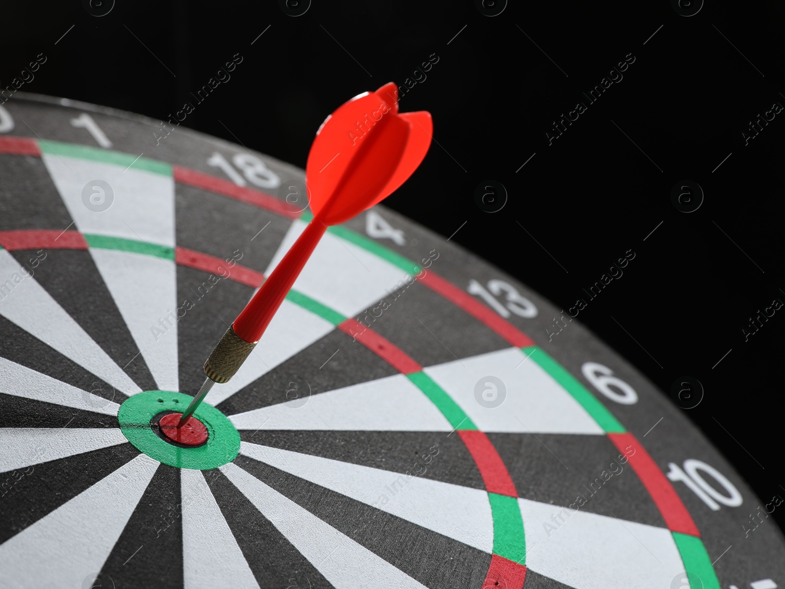 Targeting. Dart board with arrow on black background, closeup Photo of Targeting. Dart board with arrow on black background, closeup