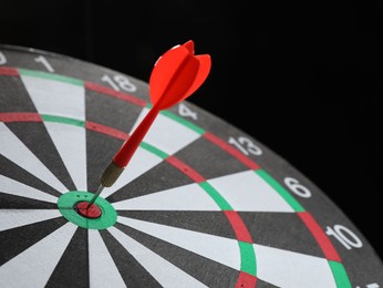 Photo of Targeting. Dart board with arrow on black background, closeup