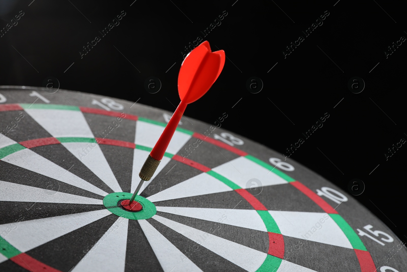 Targeting. Dart board with arrow on black background, closeup Photo of Targeting. Dart board with arrow on black background, closeup
