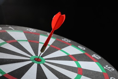 Photo of Targeting. Dart board with arrow on black background, closeup