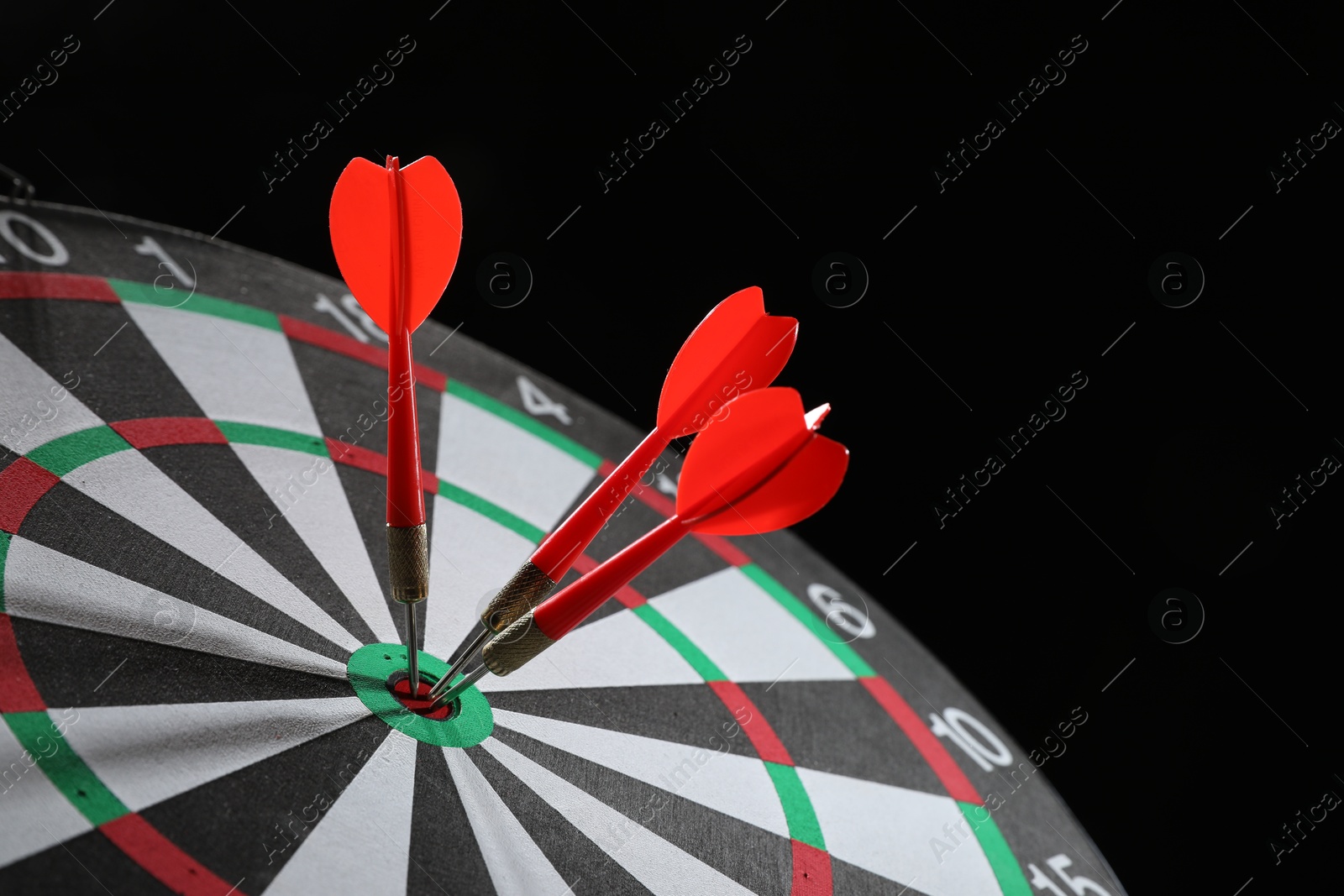 Targeting. Dart board with arrows on black background, closeup Photo of Targeting. Dart board with arrows on black background, closeup
