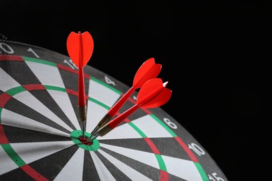 Photo of Targeting. Dart board with arrows on black background, closeup