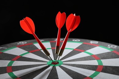Photo of Targeting. Dart board with arrows on black background, closeup