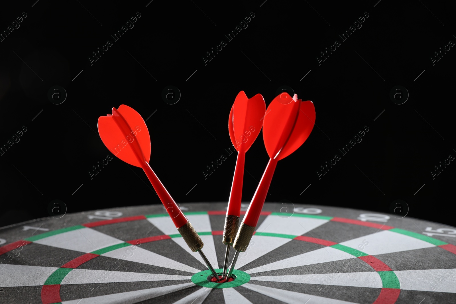 Targeting. Dart board with arrows on black background, closeup Photo of Targeting. Dart board with arrows on black background, closeup