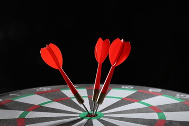Photo of Targeting. Dart board with arrows on black background, closeup