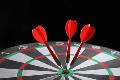 Photo of Targeting. Dart board with arrows on black background, closeup