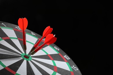 Photo of Targeting. Dart board with arrows on black background, closeup. Space for text