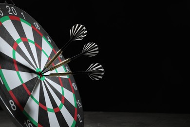 Photo of Targeting. Dart board with arrows on dark background, closeup. Space for text