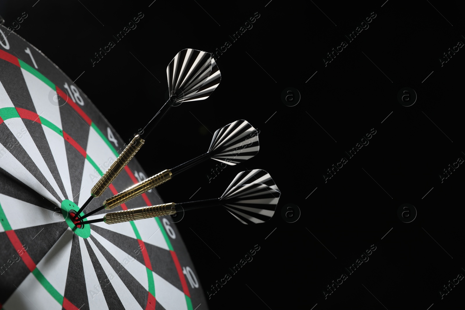 Targeting. Dart board with arrows on black background, closeup. Space for text Photo of Targeting. Dart board with arrows on black background, closeup. Space for text