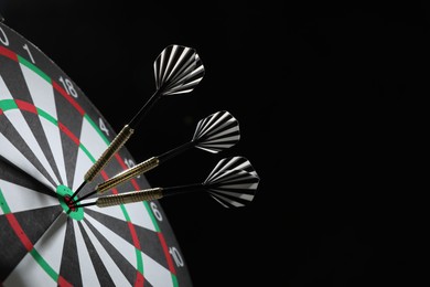 Photo of Targeting. Dart board with arrows on black background, closeup. Space for text