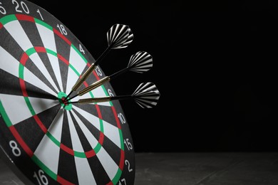 Photo of Targeting. Dart board with arrows on dark background, closeup. Space for text