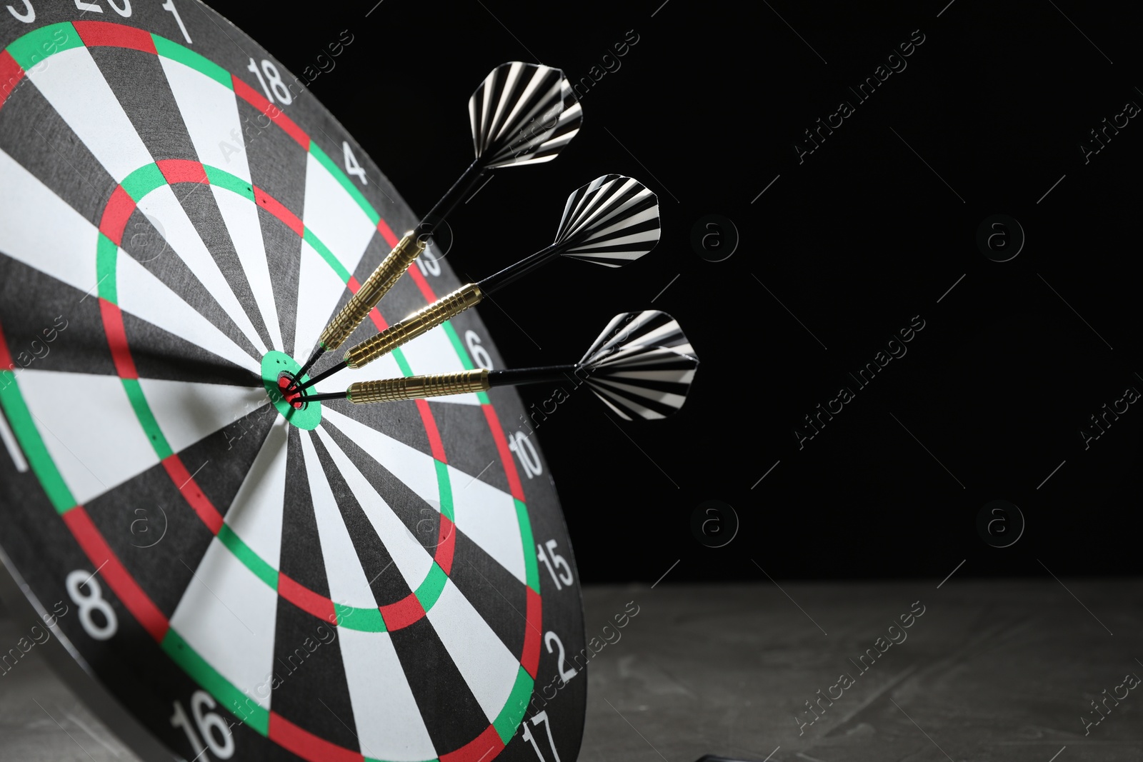 Targeting. Dart board with arrows on dark background, closeup. Space for text Photo of Targeting. Dart board with arrows on dark background, closeup. Space for text