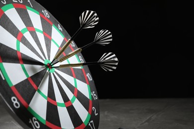 Photo of Targeting. Dart board with arrows on dark background, closeup. Space for text
