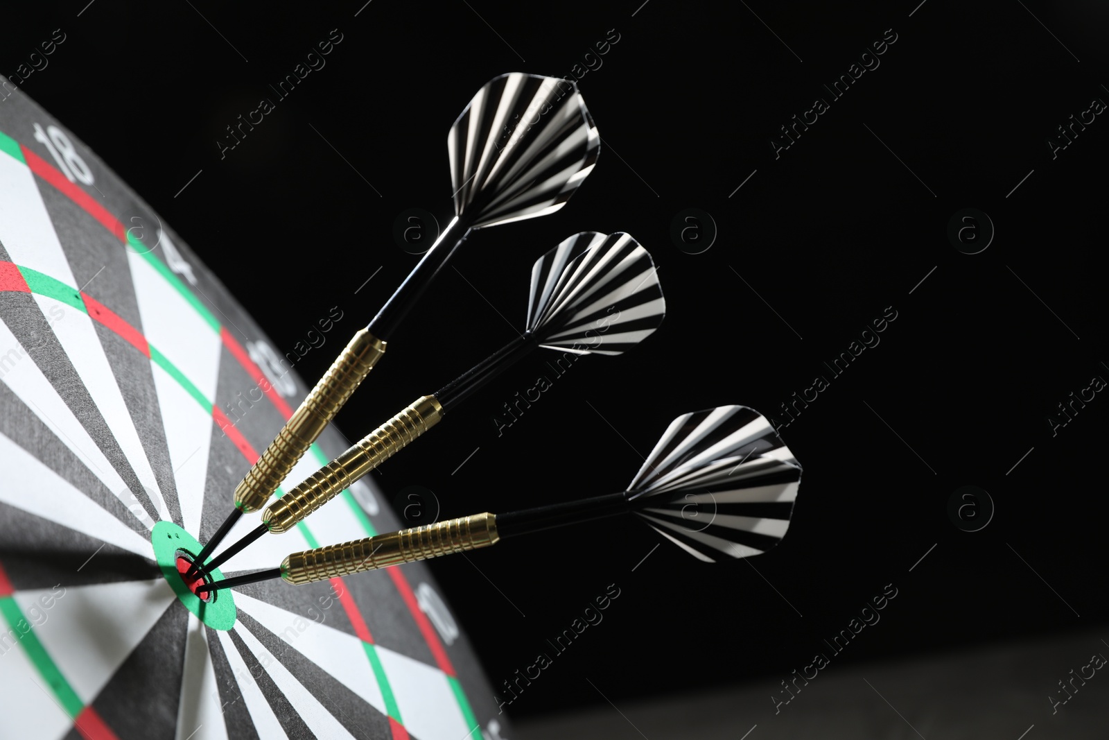 Targeting. Dart board with arrows on dark background, closeup Photo of Targeting. Dart board with arrows on dark background, closeup