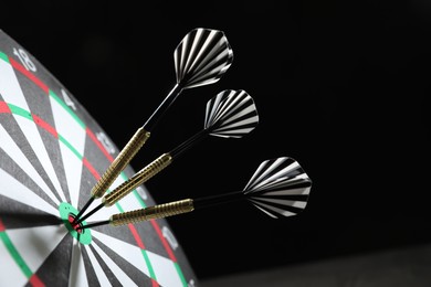 Photo of Targeting. Dart board with arrows on dark background, closeup